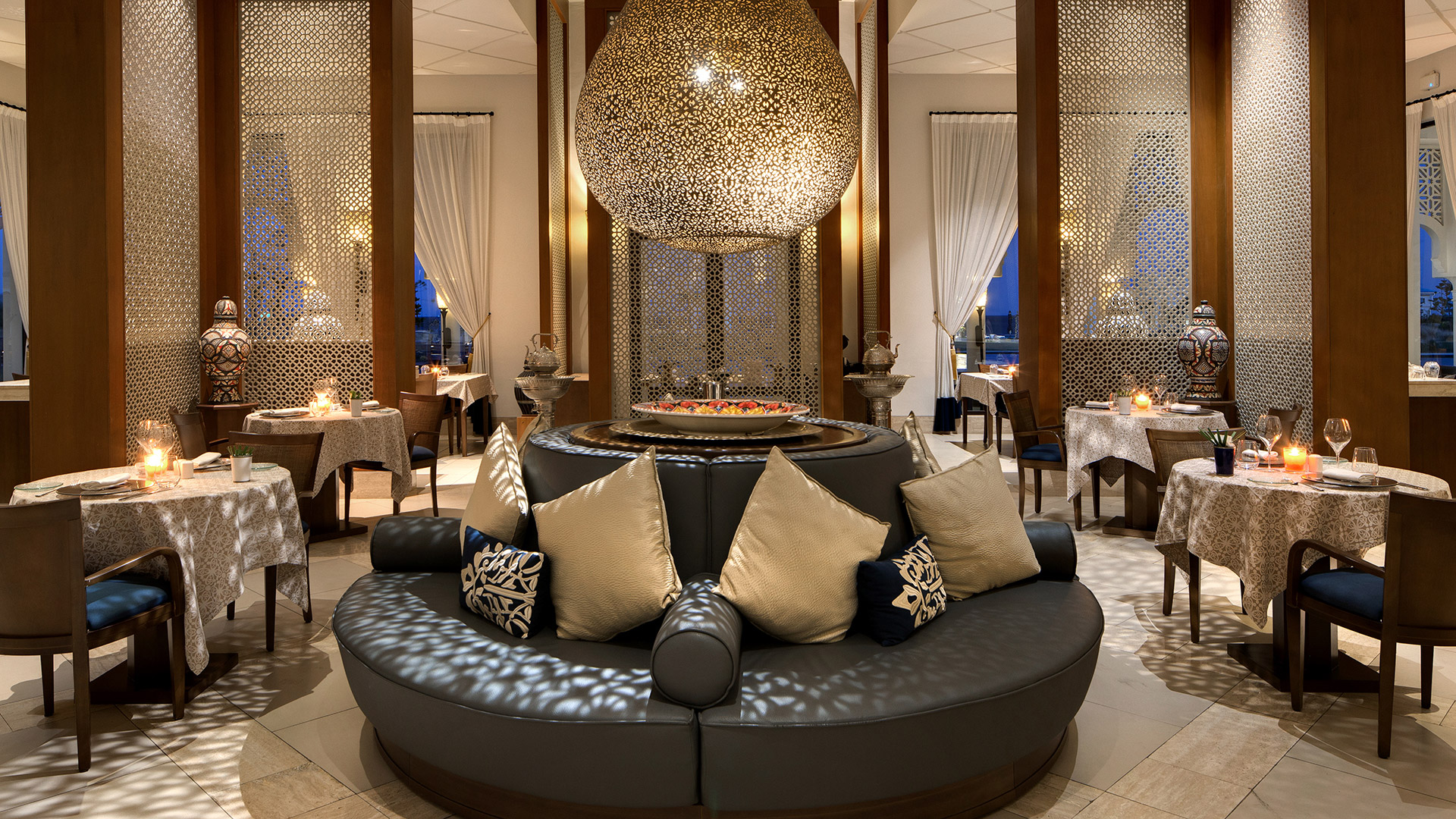 Elegant Tingitana dining area with ornate lantern, plush seating, and candlelit tables at Banyan Tree Tamouda Bay.