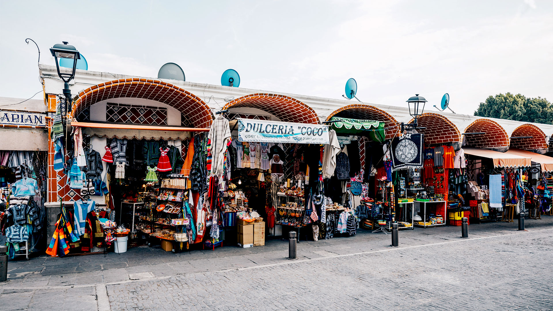 Market stalls display colorful textiles and goods, enhancing the vibrant atmosphere of Banyan Tree Puebla.
