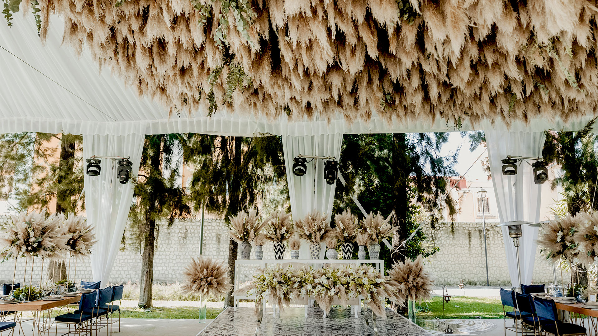 Lush floral arrangement adorns patio at Banyan Tree Puebla's wedding venue, beneath canopy with elegant decor.