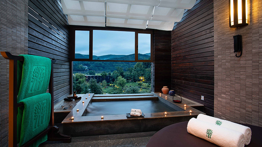 Luxurious spa tub surrounded by candles overlooking serene mountains at Banyan Tree Tengchong.