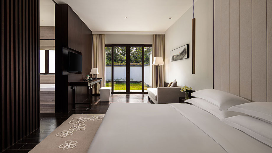 Luxurious Banyan Tree Huangshan Resorts suite; bed facing garden; modern decor and serene ambience.