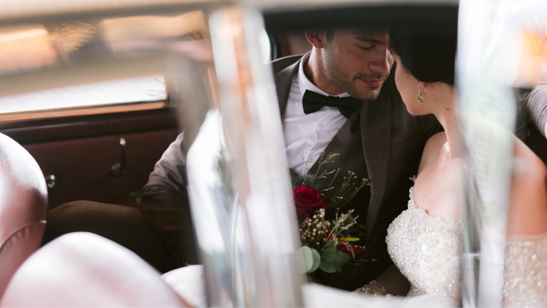 Couple sitting closely in a car, bouquet in hand, at Banyan Tree Tamouda Bay wedding.